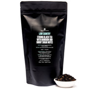 Black tea package with a scoop of tea leaves on a white background
