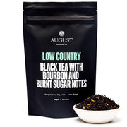 Black tea package with 'August' branding and tea leaves in a bowl on a white background