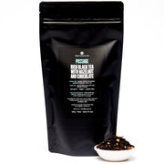 Black tea packaging with a small bowl of tea leaves on a white background