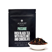 Black tea packaging with 'August' branding and a bowl of tea leaves on a white background