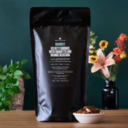 Black coffee bag labeled 'Barritz' with a bowl of roasted coffee beans on a wooden table.