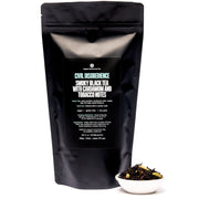 Black tea package with text and a small bowl of tea leaves on a white background