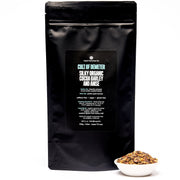 Black bag of 'Cult of Demeter' organic cereal with a small bowl of cereal on a white background