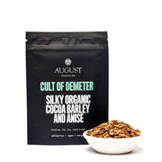 August tea package with 'Cult of Demeter' tea and a bowl of tea leaves on a white background