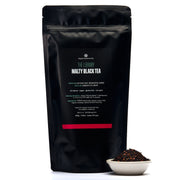 Black tea packaging with visible text and a small bowl of tea leaves on a white background