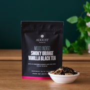 August tea package with loose tea leaves on a wooden surface