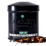 Black tea canister labeled 'August' with tea leaves spilling out on a white background