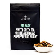 Black August tea bag with tea leaves in a bowl on a white background