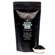 Black tea packaging with visible text and a small bowl of tea leaves on a white background