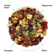 Assorted dried fruit and herb tea blend with labeled ingredients on a white background