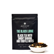 Black tea package with text and a small bowl of tea leaves on a white background