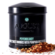 Black tea canister labeled 'August Uncommon Tea' with tea leaves on a white background