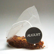 Tea bag with 'AUGUST' label on a white background