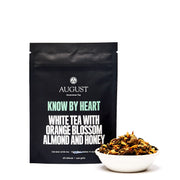 Black tea packaging with white text and a bowl of tea leaves on a white background