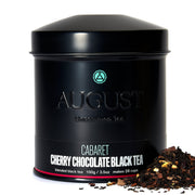 Black tea canister with 'August Uncommon Tea' branding and loose tea leaves on a white background
