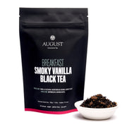 Black tea package labeled 'August' with a small bowl of tea leaves on a white background