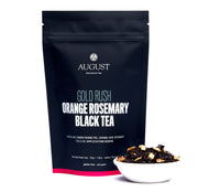August Gold Rush Orange Rosemary Black Tea package with tea leaves in a bowl on a white background