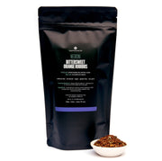 Black tea packaging with visible text and a small bowl of tea leaves on a white background