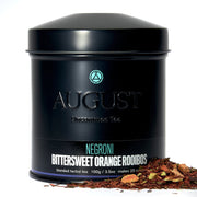 Black tea canister labeled 'August' with tea leaves on a white background