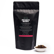 Black tea packaging with a bowl of tea leaves on a white background