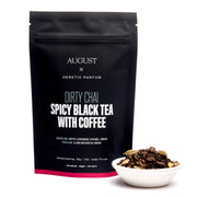 Black tea package labeled 'August x Heretic Parfum' with a bowl of tea leaves on a white background