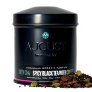 Black tea canister labeled 'August Uncommon Tea' with 'Heretic Parfum' collaboration, featuring 'Dirty Chai' description.