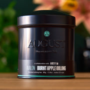 August Uncommon Tea canister with branding and product details on a wooden surface.