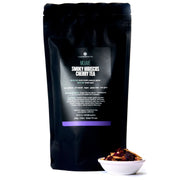 Black tea package labeled 'Smoky Hibiscus Cherry Tea' with loose tea leaves in a small bowl on a white background