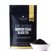 Tea package labeled 'August Decaf Low Country Bourbon Sugar Black Tea' with a small bowl of tea leaves on a white background.