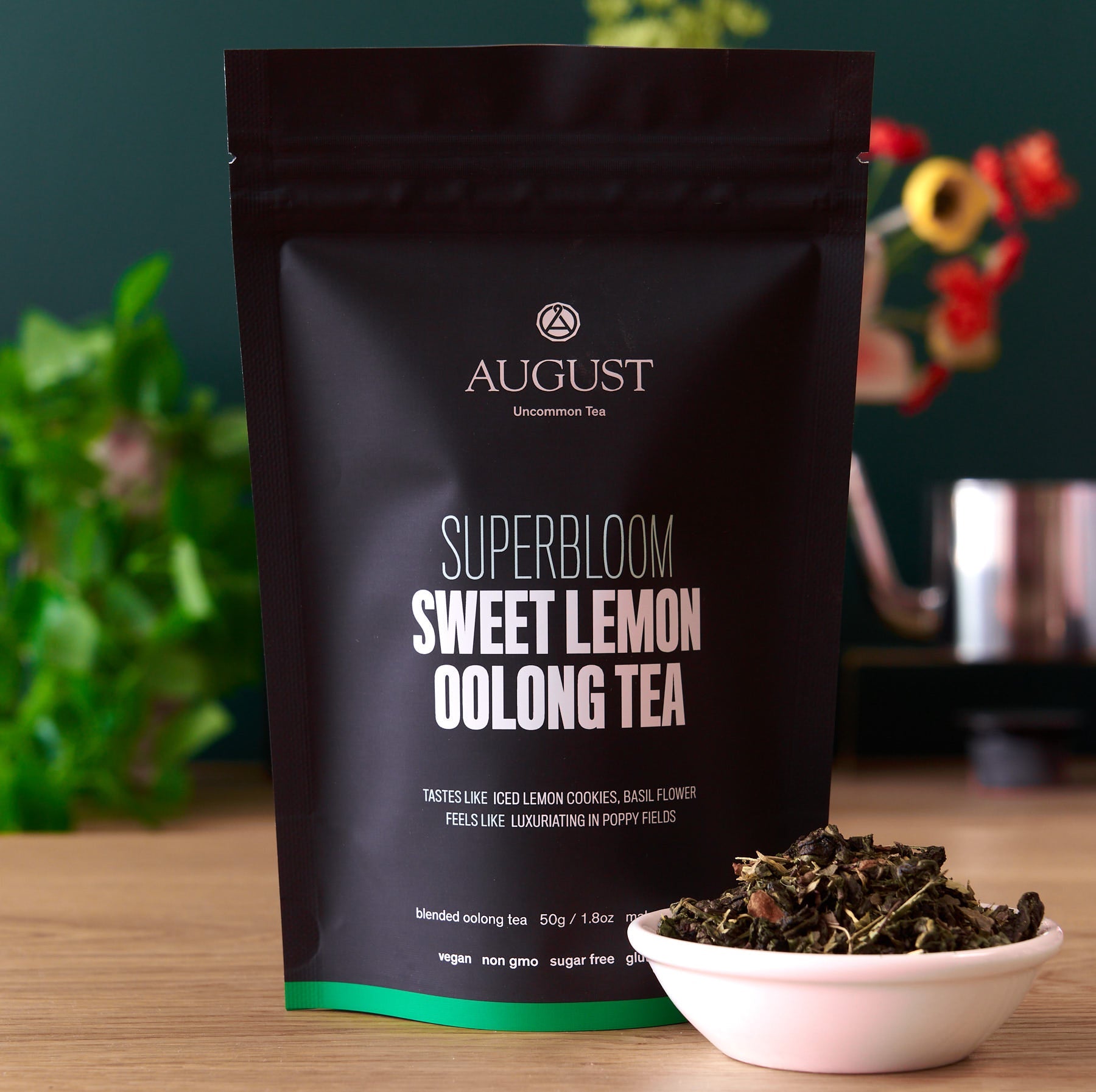 August Superbloom Sweet Lemon Oolong Tea package with tea leaves in a bowl on a wooden surface.