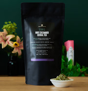 Olympus Mint Cucumber Herbal Tea package with loose tea in a bowl on a wooden surface.
