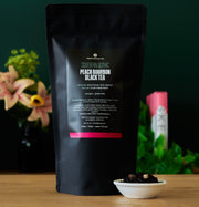 Black tea package with 'Southern Gothic' branding on a wooden surface with flowers in the background