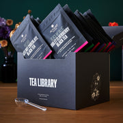Box of 'Tea Library' with assorted tea packages on a wooden surface.