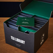 Tea library box with tea bags and a card on a wooden surface