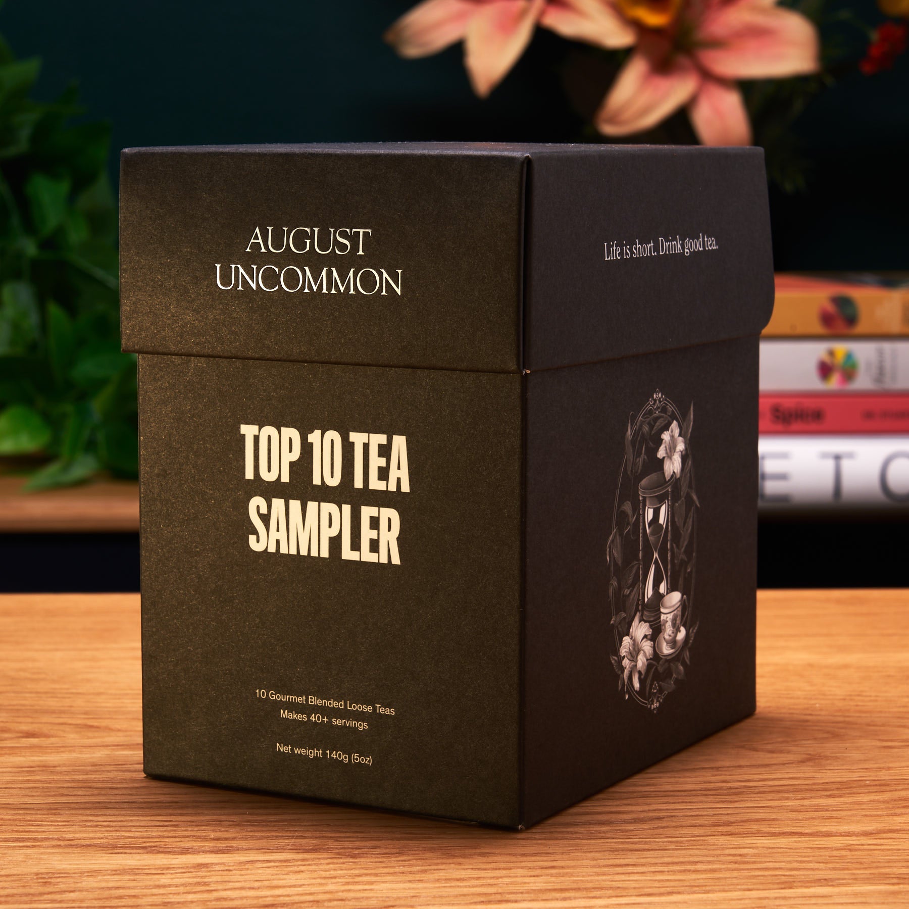 Black tea sampler box with 'August Uncommon' branding on a wooden surface.
