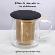 Glass mug with gold infuser and black silicone lid on a white background