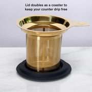 Gold mesh strainer with lid on a white background
