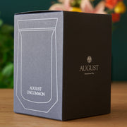 Black box with 'August Uncommon' branding on a wooden surface
