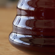 Glass bottle with 'AUGUST UNCOMMON' branding on a wooden surface