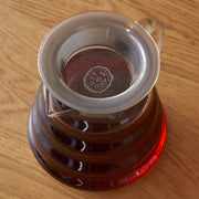Clear glass teapot with a red base on a wooden surface