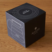 Black box packaging for an August product on a wooden surface