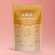 Package of 'a dash Golden Immunity' turmeric latte powder on a pink background