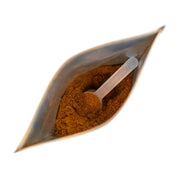 Spice packet with a spoon filled with brown powder on a white background