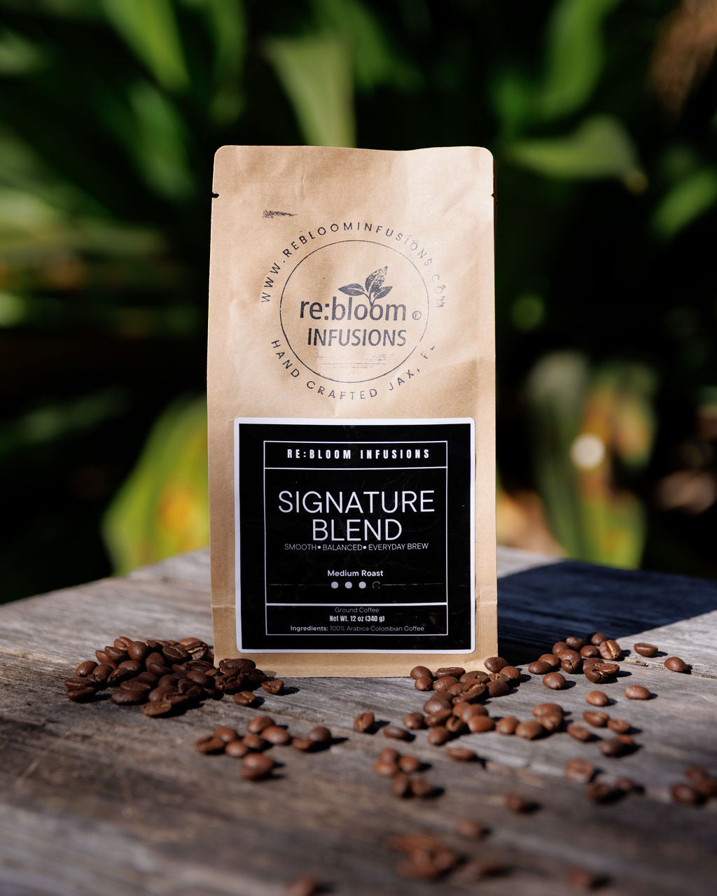 Kraft paper coffee bag with 're:bloom Infusions' branding on a wooden surface with scattered coffee beans.