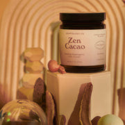 Jar of 'Zen Cacao' powder on a decorative stand with a blurred background