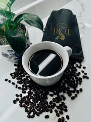 White cup of coffee with a bag of Tori coffee beans on a marble surface.