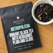 August Metropolitan black tea package with a bowl of tea leaves on a wooden surface