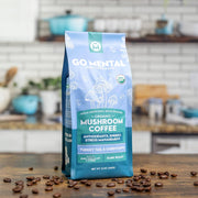 Go Mental Mushroom Coffee package on a kitchen counter with coffee beans around