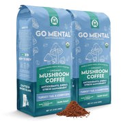 Two packages of Go Mental Mushroom Coffee with a small amount of coffee grounds in front.