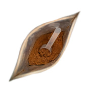 Metallic scoop with brown powder inside on a white background